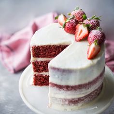 a red velvet cake with white frosting and fresh strawberries on the top slice