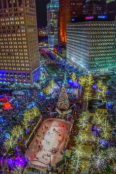 an aerial view of a city at night with christmas lights on the trees and skating rink