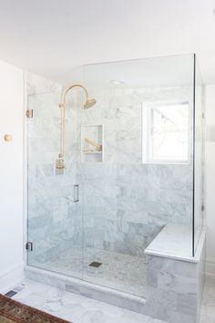 a walk in shower sitting next to a white wall and floor with a rug on the floor