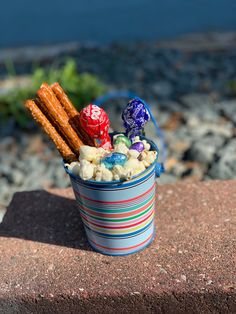 a bucket filled with candy and candies sitting on top of a rock