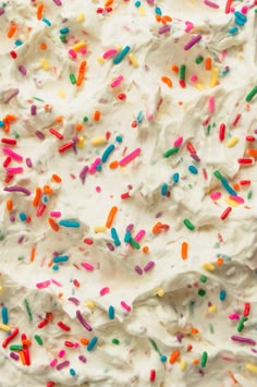 white frosted cake with sprinkles and multicolored icing on top