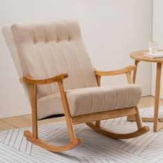 a wooden rocking chair sitting on top of a white rug next to a small table