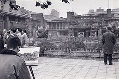 an old black and white photo of people standing in front of buildings with paintings on easels