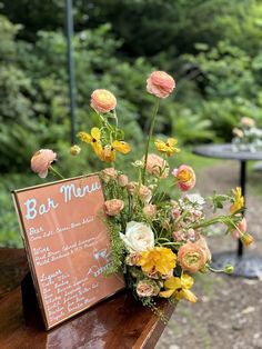 a wooden bench with flowers on it and a sign that says bar menu next to it