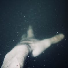 a person's hand reaching for something in the air with water droplets on it