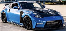 a blue nissan sports car parked in front of a bridge