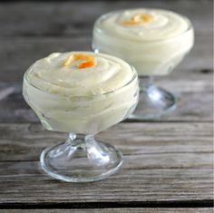 two glasses filled with dessert sitting on top of a wooden table