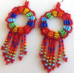 two pairs of colorful beaded earrings on a white surface with one pair hanging off the side