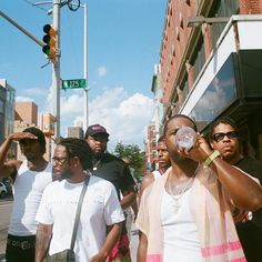 a group of men standing on the side of a road next to a traffic light