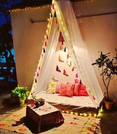 a bed that has some lights on it in the middle of a room with plants