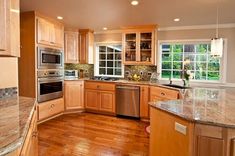 a kitchen with wooden cabinets and stainless steel appliances, wood flooring and granite counter tops