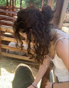 a woman bending over to pet a sheep