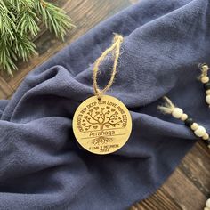 a wooden ornament hanging on a blue cloth next to a pine tree and bead necklace