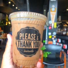 a person holding up a cup of ice cream in front of a restaurant sign that says, please & thank you