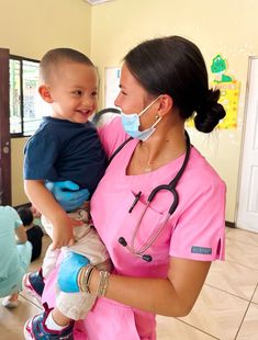 a woman in scrubs holding a small child