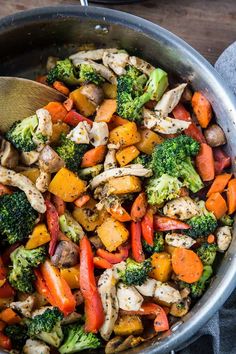 chicken, broccoli, and carrots in a pan with a wooden spoon