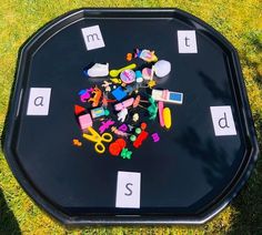 a black table topped with lots of different types of toys on top of green grass