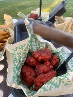 a person holding a fork near some food in a basket on a table with napkins