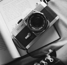 an old camera sitting on top of a book next to a pair of black shoes