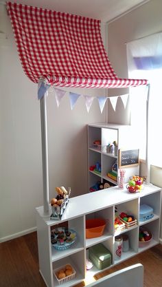 a child's playroom with toys and accessories on shelves, including a red gingham awning