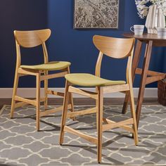 two wooden chairs sitting next to each other on top of a carpeted floor in front of a blue wall