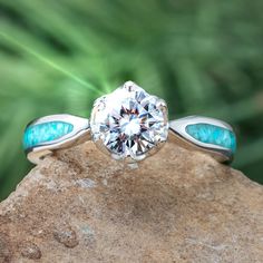 A brilliant moissanite sits atop this sleek platinum engagement ring. Crushed turquoise perfectly complements the moissanite stone, allowing the color to shine throughout this unique ring. Need a matching wedding band for your unique engagement ring? Our Platinum and Diamond Women's Wedding Band (SKU 3885PT) pairs perfectly with this design. RING LAYOUTRing Width: 3.5 mmRing Sleeve: PlatinumRing Profile: RoundRing Finish: Polished 0.75 mm Platinum2 mm Crushed Kingman Blue Turquoise0.75 mm Platin Teal Promise Ring, Luxury Turquoise Diamond Ring With Center Stone, Turquoise Diamond Rings With Center Stone, Turquoise Diamond Anniversary Ring, Turquoise Ring With Center Stone For Anniversary, Anniversary Turquoise Ring With Center Stone, Turquoise Engagement Ring, Turquoise Diamond Rings, Turquoise Wedding Rings