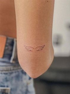 a woman's arm with an angel wing tattoo on the left side of her body