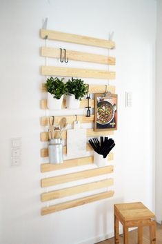 a wooden shelf with pots and pans hanging on it's wall next to a small stool