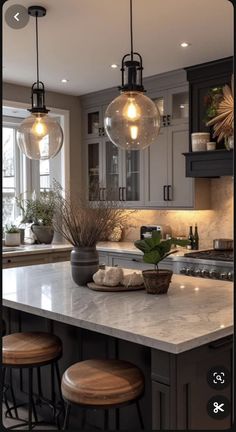 a kitchen island with stools and lights hanging from it's ceiling above it