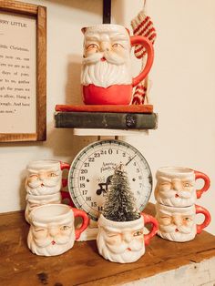 santa claus mugs and other christmas decorations sit on a shelf next to a clock