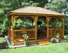 a wooden gazebo sitting on top of a lush green field