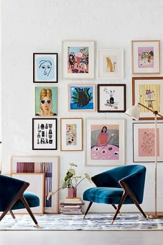 two blue chairs sitting in front of a wall with pictures on it and an orange frame