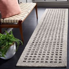 a white rug on the floor next to a chair and potted plant in front of a window