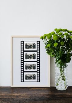 a vase filled with flowers sitting on top of a wooden table next to a framed photo