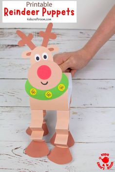 a hand holding up a paper reindeer puppet on top of a white wooden table with text overlay that says, printable reindeer puppets