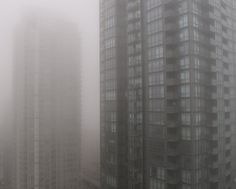 two tall buildings in the fog on a cloudy day