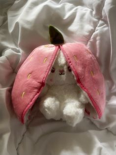 a stuffed animal with a pink hat on it's head sitting in the middle of a bed