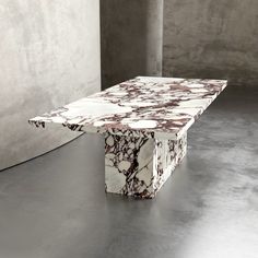 a marble table sitting on top of a floor next to a concrete wall in an empty room