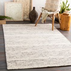 a large white rug on the floor in front of a chair and potted plant