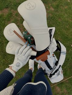 a pair of white golf gloves on the back of a person's feet with their golf club and driver's mitts