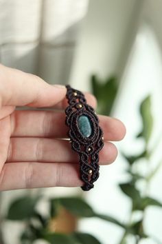 a hand holding a beaded bracelet with a turquoise stone in it's center