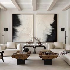 a living room filled with white couches and two large paintings on the wall above them