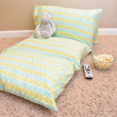 a child's bed with a stuffed animal on it and popcorn bowl next to it