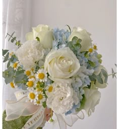 a bouquet of white and blue flowers in someone's hand