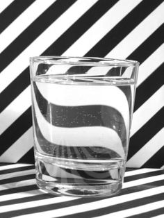 a glass filled with water sitting on top of a black and white striped table cloth