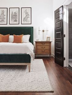 a bedroom with white walls and wood flooring has a green headboard on the bed