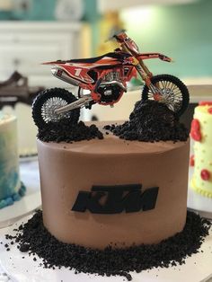 a cake with dirt bike on top and the number m in the middle is made out of chocolate frosting