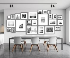 a dining room table surrounded by white chairs and framed pictures on the wall above it