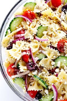 pasta salad with cucumbers, red onions, and olives in a glass bowl