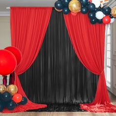 a red curtain with black drapes and balloons on the floor in front of it